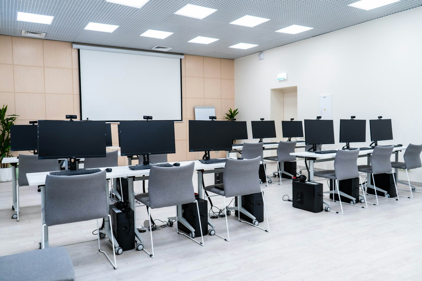 Empty computer classroom with rows of monitors and a projector screen, representing the Caribbean's AI literacy and workforce training gap