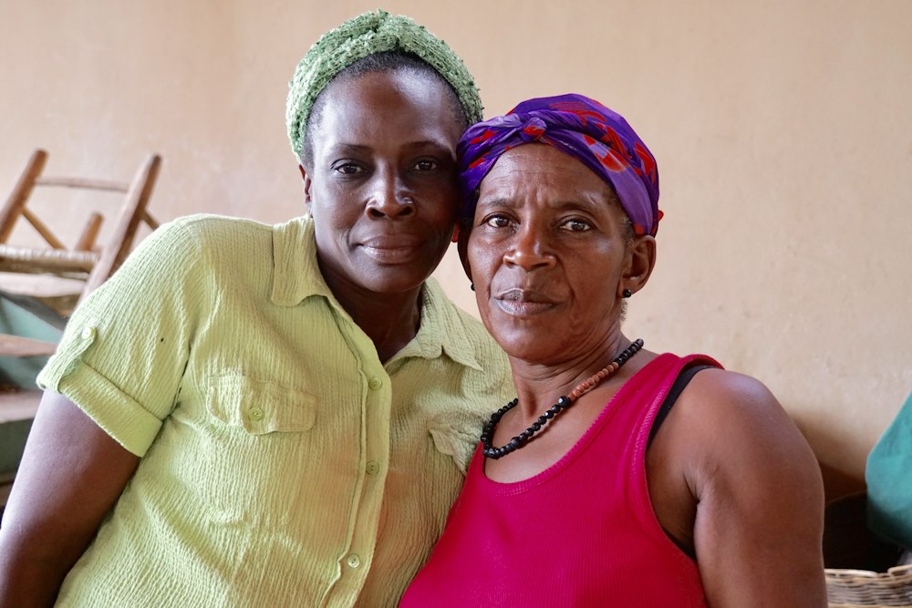 Two women standing together at a market in Haiti