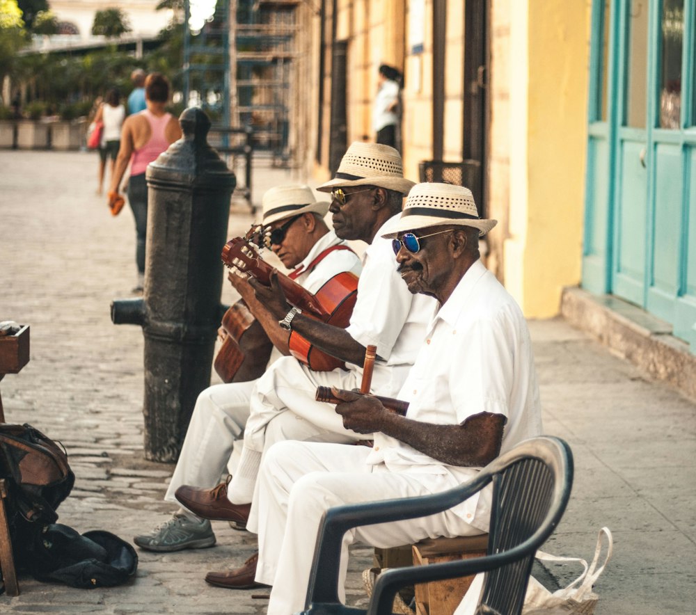 Three older musicians playing guitar on a street in Havana