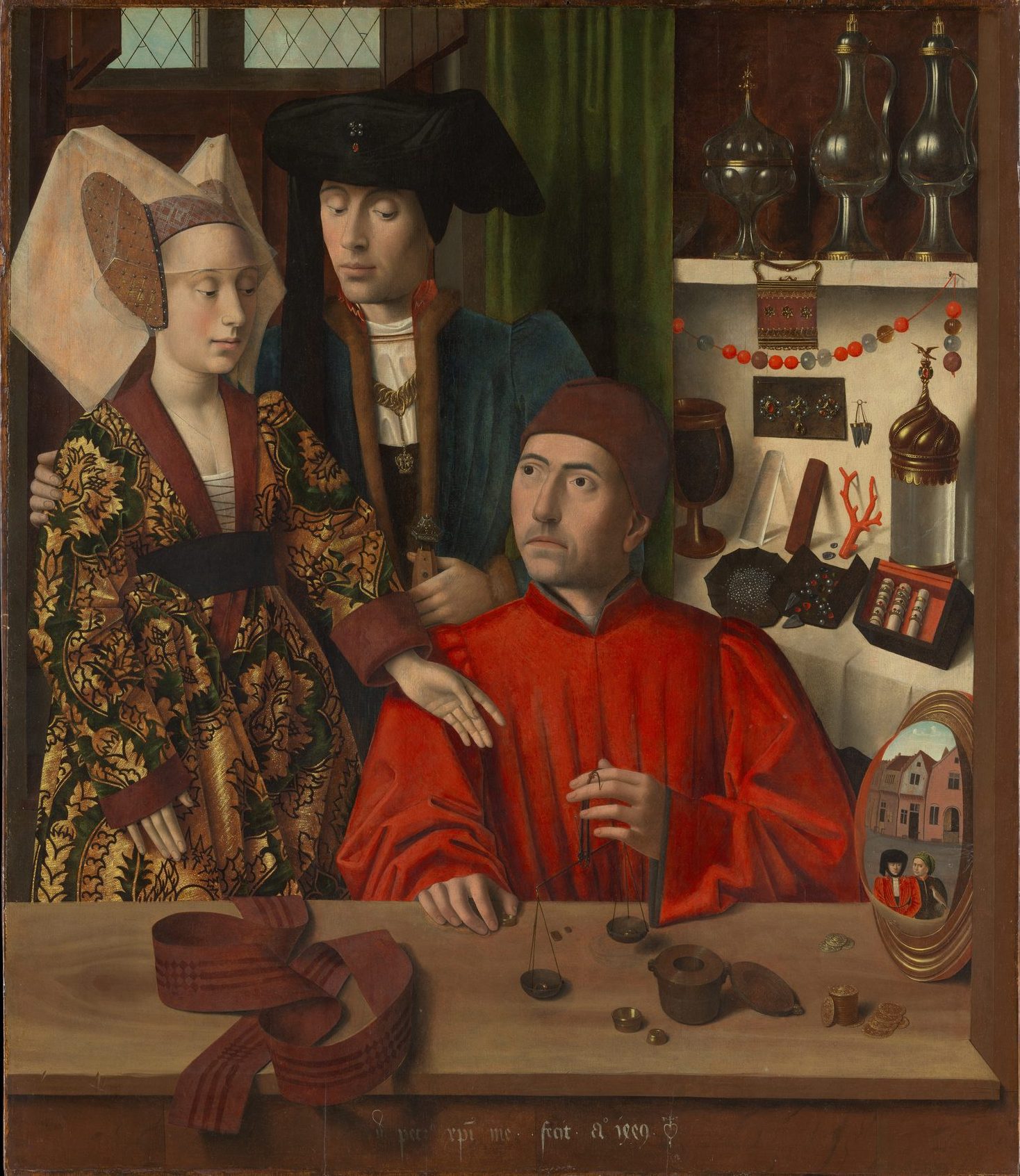 A goldsmith in a red robe weighs a ring on scales for a young couple standing at his counter